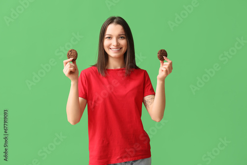 Beautiful young woman with tasty cookies on green background