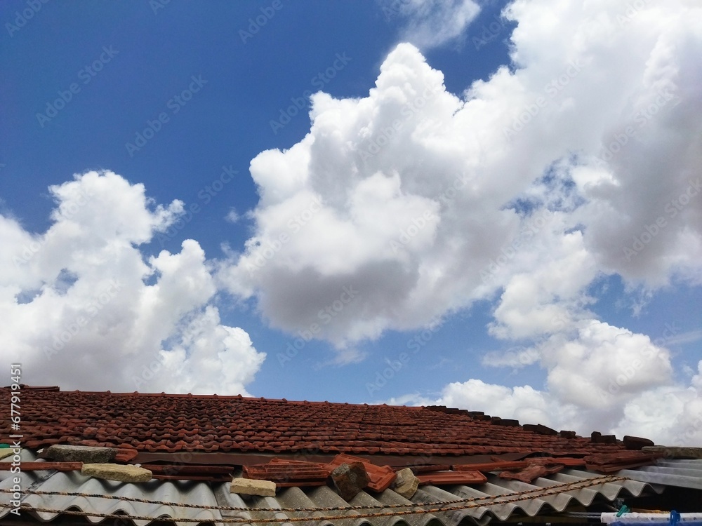 Rooftop of an old house under the blue sky with white clouds