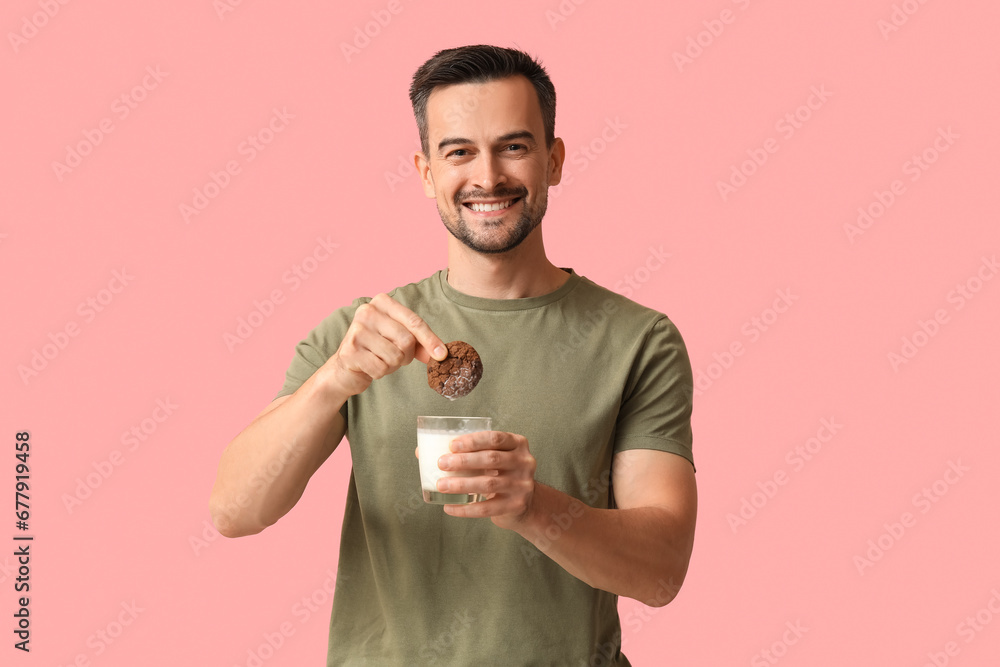 Handsome man with tasty cookie and glass of milk on pink background Handsome man with tasty cookie and glass of milk on pink background