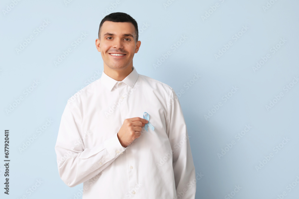 Handsome man with blue ribbon on color background. Prostate cancer concept Handsome man with blue ribbon on color background. Prostate cancer concept