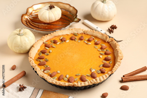 Delicious pumpkin tart with almond, seeds and cinnamon on beige background