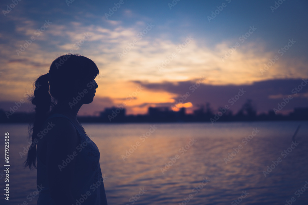 silhouette of a girl on the beach looking sunset.