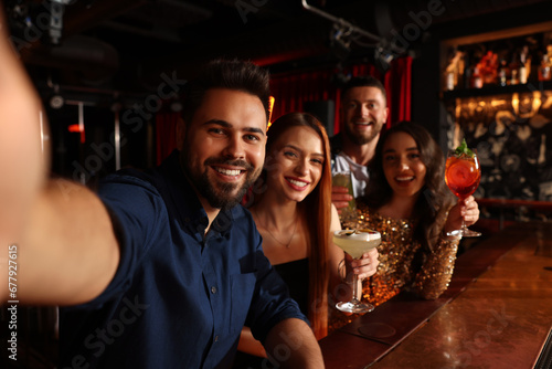 Happy friends with cocktails taking selfie together in bar photo