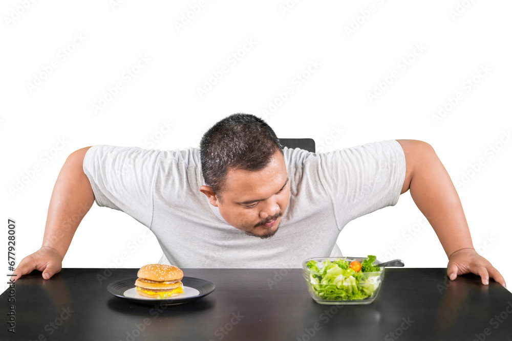 Confused overweight man choosing between a bowl of salad or a cheese burger Confused overweight man choosing between a bowl of salad or a cheese burger