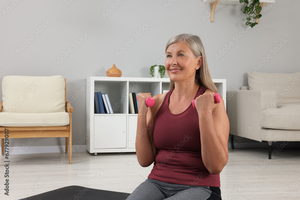 Senior woman exercising with dumbbells at home. Sports equipment Senior woman exercising with dumbbells at home. Sports equipment