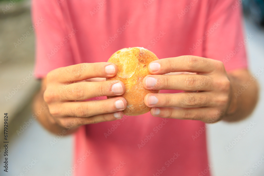 A man's hand holds a round bun, snack and fast food concept. Selective focus on hands with blurred background A man's hand holds a round bun, snack and fast food concept. Selective focus on hands with blurred background