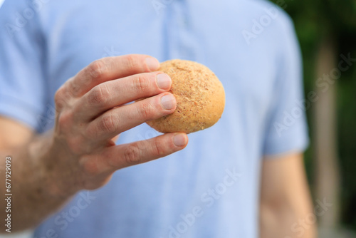 Man's hand holds mini bread, snack and fast food concept. Selective focus on hands with blurred background
