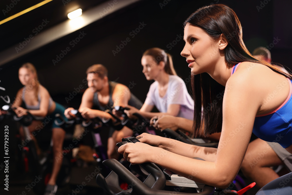 Group of people training on exercise bikes in fitness club