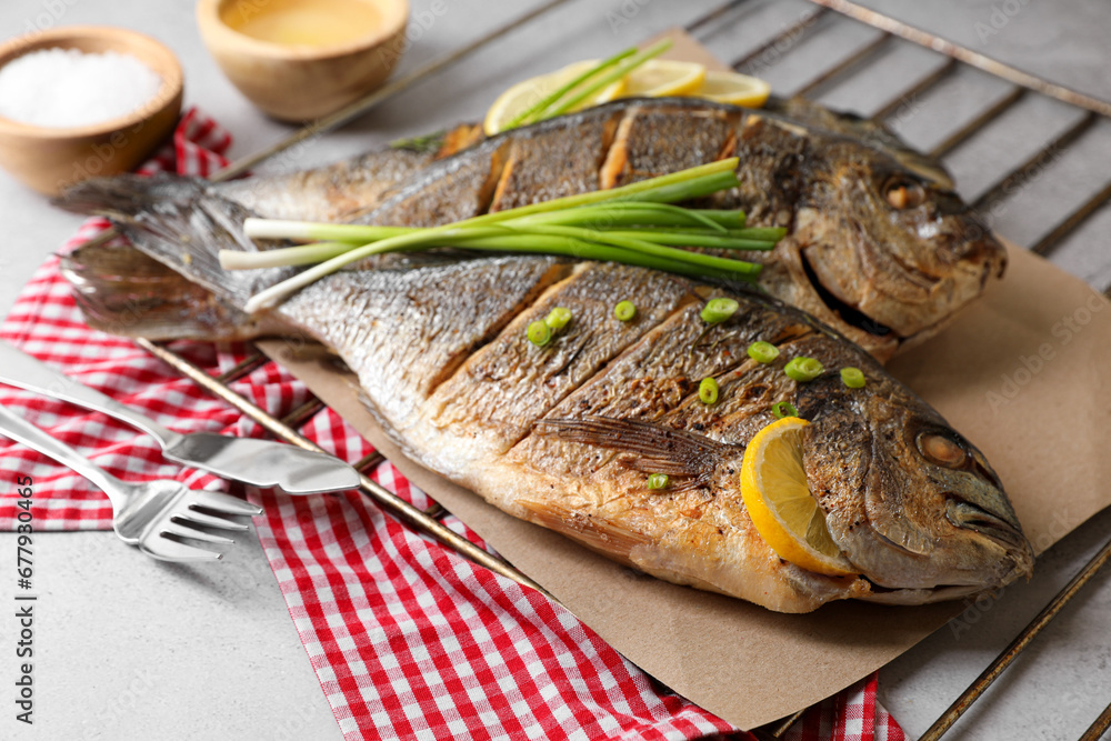 Seafood. Delicious baked fish served with green onion and lemon on light table, closeup Seafood. Delicious baked fish served with green onion and lemon on light table, closeup