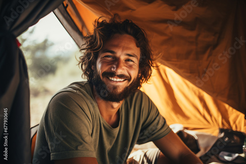 Man sitting inside tent with a smile on his face during camping trip. Created with Generative AI technology
