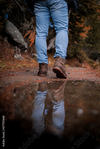 A male hiker crossing the stream walking by the creek adventure travel hiking trail forest.