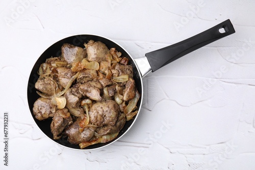 Pan with tasty fried chicken liver and onion on white textured table, top view