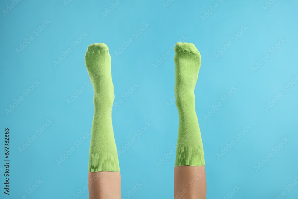 Woman in stylish lime socks on light blue background, closeup Woman in stylish lime socks on light blue background, closeup