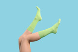 Woman in stylish lime socks on light blue background, closeup