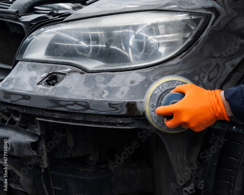 A mechanic sands the putty on a car body with a machine. Repair after an accident.  © Михаил Решетников