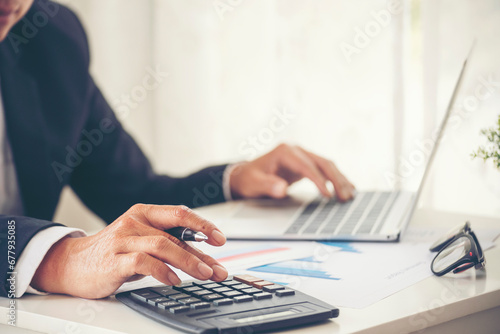 Close up man hands Asian businessman  calculating number, audit planning on business report Asian Business man hands using calculator counting tax financial bill. Tax audit Finacial concept photo