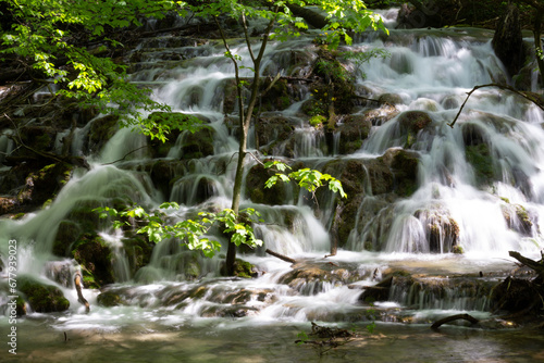 Fototapeta Naklejka Na Ścianę i Meble -  A lively cascade of water gushes down a small waterfall