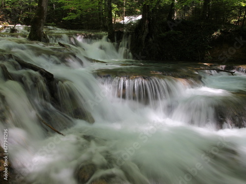 Fototapeta Naklejka Na Ścianę i Meble -  A serene waterfall cascading down moss-covered rocks surrounded by tall trees