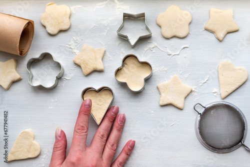 Top view of woman hands cooking a gingerbread cookie in the form of heart, star, cloud and flower. Christmas and New Year concept, festive preparations for winter hilodays