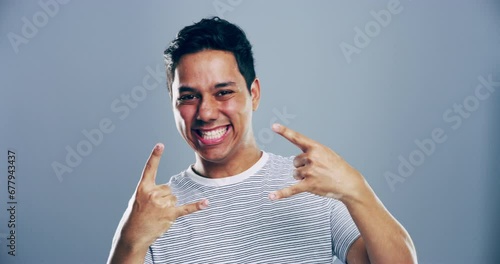 Portrait, rock and roll with man, hand sign and artist with heavy metal music on a grey studio background. Face, person and model with creativity, culture or freedom with mockup space, symbol or punk photo
