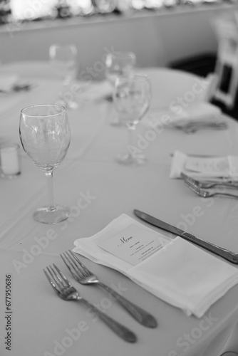 An elegantly decorated table at a wedding reception with silverware  napkin and menu on a table with empty wine glasses