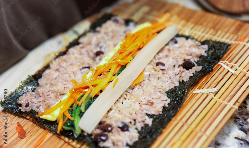 kimbap making, a cherished Korean culinary tradition. Skilled hands roll rice, vegetables, and seaweed, crafting delicious, nutritious bites for an authentic dining experience kimbap making, a cherished Korean culinary tradition. Skilled hands roll rice, vegetables, and seaweed, crafting delicious, nutritious bites for an authentic dining experience