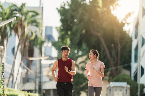 Two Asian young athlete man and woman in sportswear jogging exercise in park outdoor. Together young couple running outdoor in the morning. Healthy exercise concept.