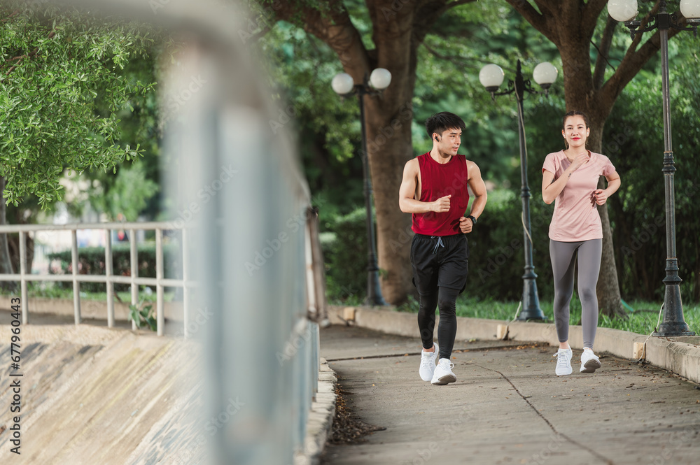 Two Asian young athlete man and woman in sportswear jogging exercise in park outdoor. Together young couple running outdoor in the morning. Healthy exercise concept. Two Asian young athlete man and woman in sportswear jogging exercise in park outdoor. Together young couple running outdoor in the morning. Healthy exercise concept.