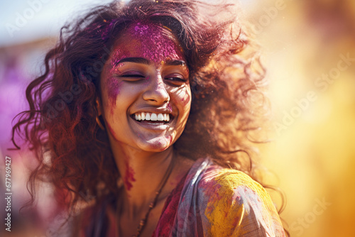 happy indian woman with holi powder on her face at holi festival bokeh style background © toonsteb