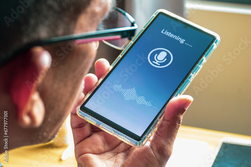 Close-up of a South Asian man talking to a voice translator mobile application. Selective focus, voice recognition and cloning concept. photo