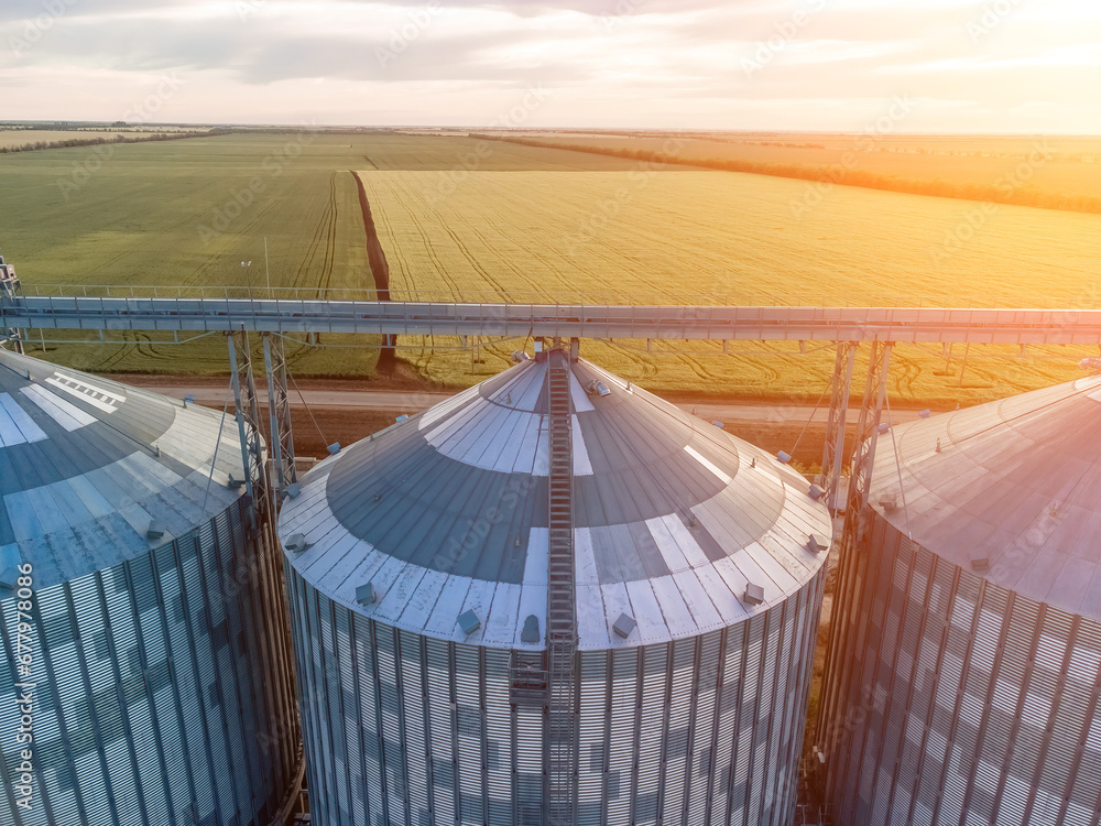 Modern metal silos on agro-processing and manufacturing plant. Aerial view of Granary elevator processing drying cleaning and storage of agricultural products, flour, cereals and grain. Nobody.