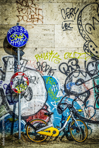Vélo de location posé contre un mur de graffitis