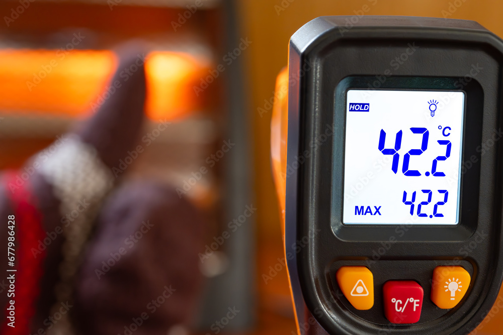 infrared thermometer shows the temperature of a glove with thumbs up gesture in front of an electric heater infrared thermometer shows the temperature of a glove with thumbs up gesture in front of an electric heater