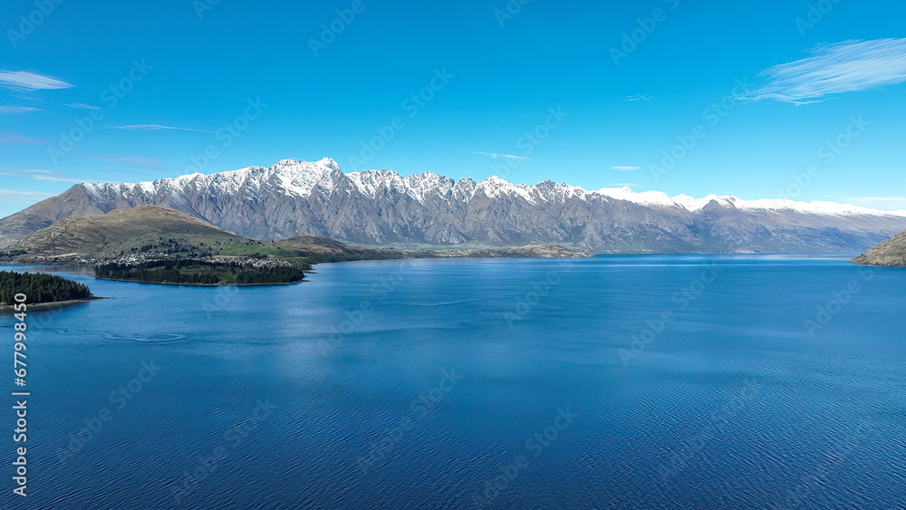 Drone panoramic view of the bays and inlets at Queenstown town at the southern end of Lake Wakatipu with a backdrop of the snow capped Remarkables Mountain range