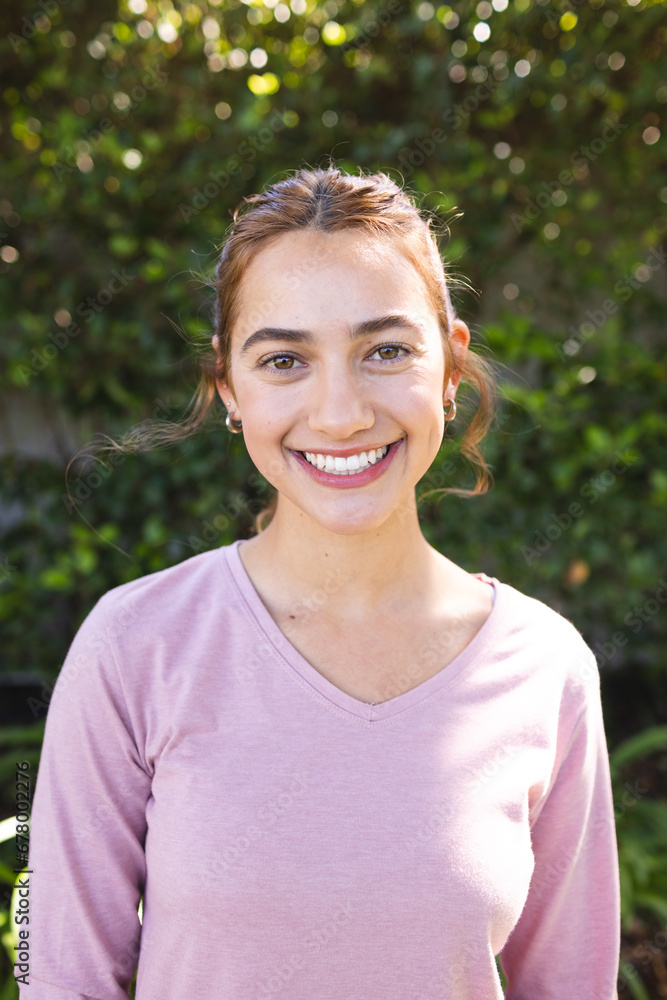Portrait of happy biracial woman with long brown hair smiling in sunny garden Portrait of happy biracial woman with long brown hair smiling in sunny garden