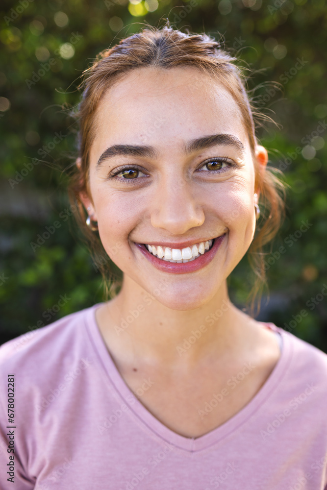 Portrait of happy biracial woman with long brown hair smiling in sunny garden Portrait of happy biracial woman with long brown hair smiling in sunny garden