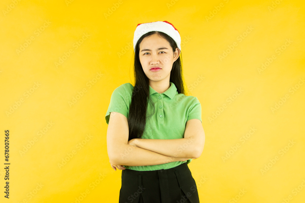 portrait of  asian woman wears a red santa claus hat isolated yellow background, christmas concept