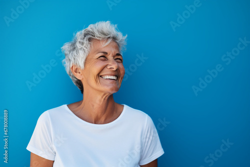portrait of a senior woman with a smiley face and short hair with a light blue color wall background 