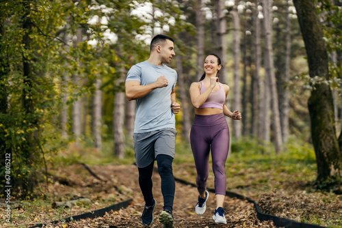 Nature fitness. A happy sporty couple is running in woods.