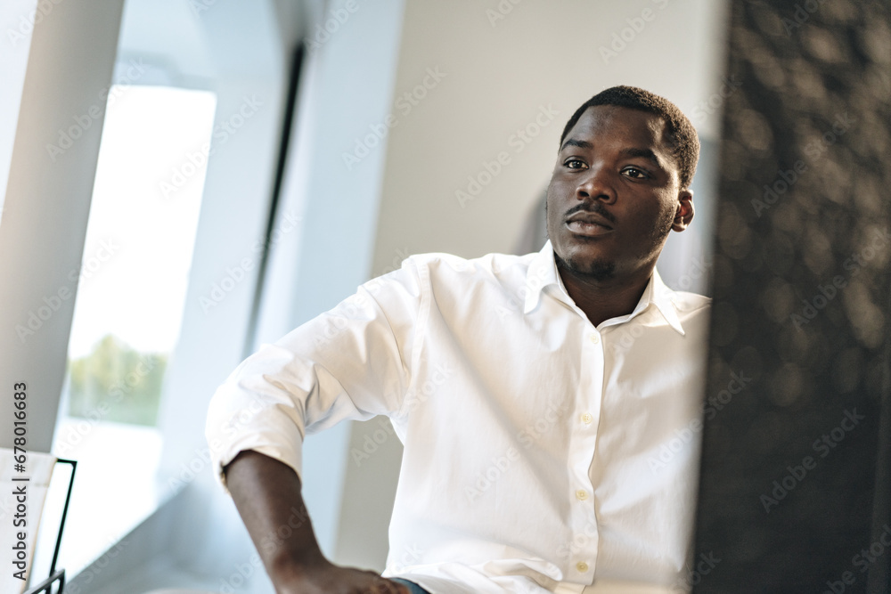 Obraz premium Young African man sitting against mirror indoors