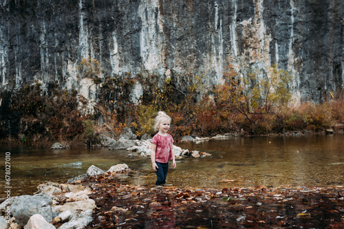 Young child wading in river during autumn day