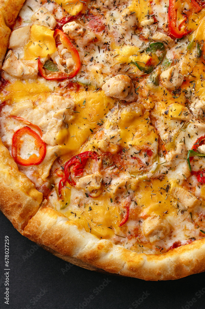 traditional Italian pizza with salami and vegetables on a black traditional Italian pizza with salami and vegetables on a black