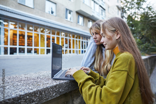 teenager girls  using laptop outdoors