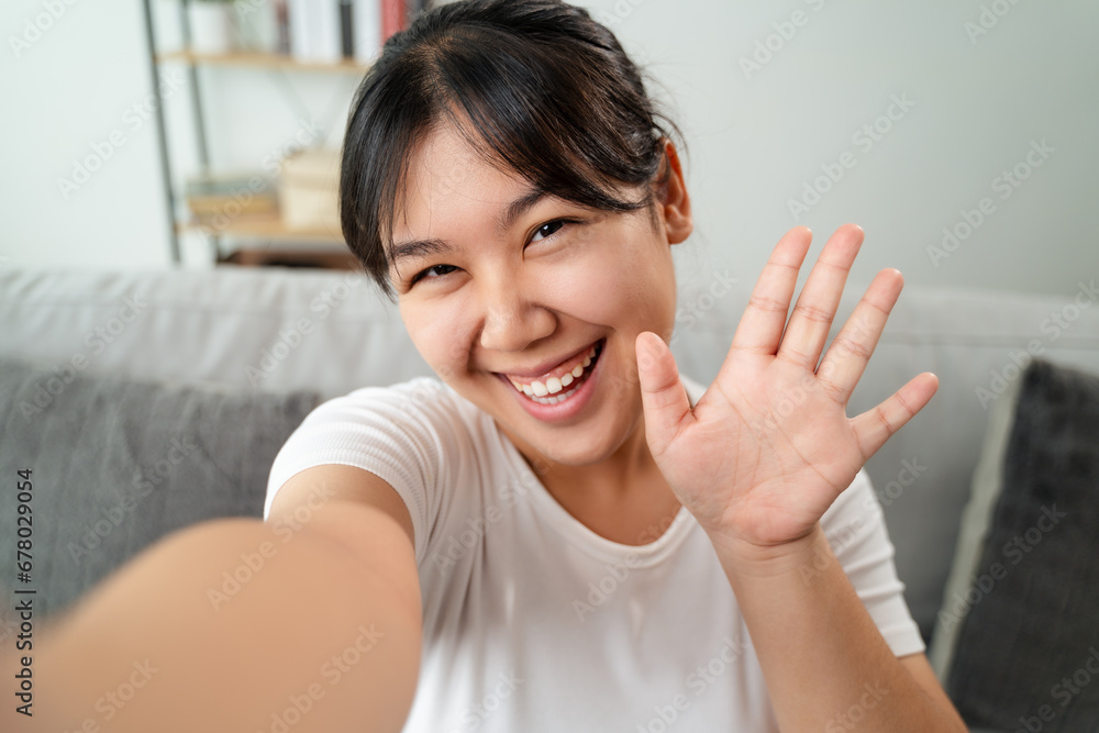 Young Asian woman using smartphone for online video conference call with friends waving hand making hello gesture Young Asian woman using smartphone for online video conference call with friends waving hand making hello gesture