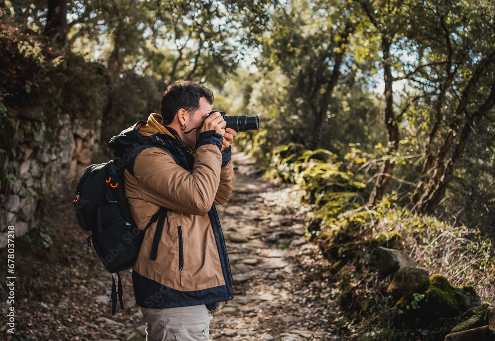 horizontal portrait of young photographer on a route through a forest path taking photographs of the surroundings horizontal portrait of young photographer on a route through a forest path taking photographs of the surroundings