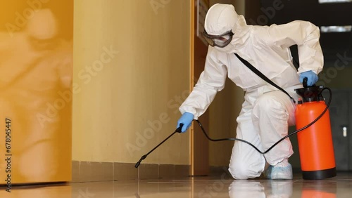Employee in a protective suit wearing protective mask disinfects room. Disinfection from bacteria virus and insects concept photo
