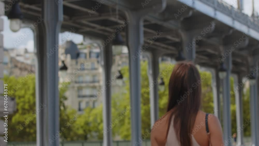 Brown haired female walking by landmark Inception Bridge in Paris, France Brown haired female walking by landmark Inception Bridge in Paris, France