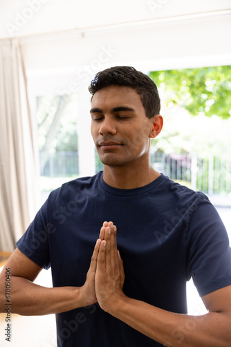 Biracial man doing yoga and meditating at home