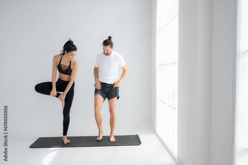Obraz premium Young couple practicing yoga in a white room of studio.