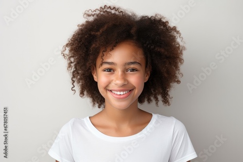 Portrait of a cheerful young girl with curly hair smiling on a light background. photo